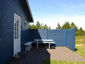 a blue house with a bench and a fence at Holiday Home Redward - 1km from the sea by Interhome in Mølby