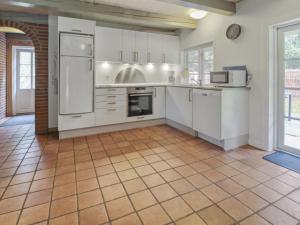 eine Küche mit weißen Schränken und einem Fliesenboden in der Unterkunft Holiday Home Volmar - 3-5km from the sea by Interhome in Kongsmark