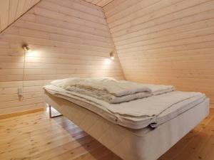 a bed in a room with a wooden wall at Holiday Home Gudmund - 3-9km from the sea by Interhome in Kongsmark