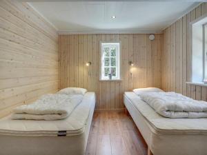 two beds in a room with wood paneling at Holiday Home Gudmund - 3-9km from the sea by Interhome in Kongsmark