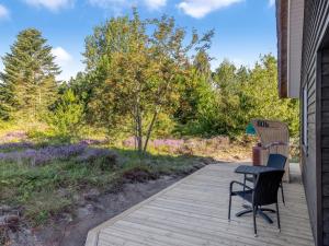 eine Holzterrasse mit 2 Stühlen und einem Tisch in der Unterkunft Holiday Home Thorulf - 3-5km from the sea by Interhome in Kongsmark + 18 Fotos