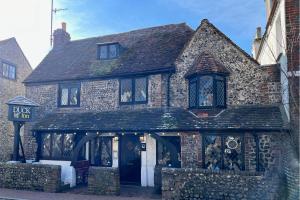 un vieux bâtiment en pierre avec une enseigne devant dans l'établissement Beautiful Mews Cottage near Brighton Seafront in Rottingdean Village, à Rottingdean
