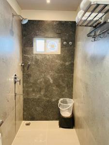 a bathroom with a shower with a window and a trash can at Hotel Skyview Suites & Studios in Hyderabad +33 photos