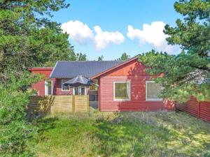 une maison rouge avec un parasol dans une cour dans l'établissement Holiday Home Dorreth - 800m from the sea by Interhome, à Mølby
