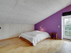 a bedroom with a white bed and purple walls at Holiday Home Henrieta - 4km from the sea by Interhome in Toftum