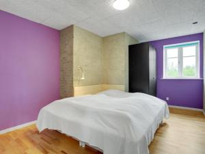 a bedroom with a white bed and purple walls at Holiday Home Henrieta - 4km from the sea by Interhome in Toftum