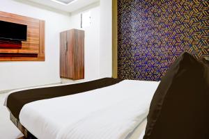 a bedroom with a white bed and a tv at Hotel O Angel Park in Ahmedabad