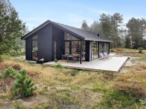 une maison noire avec une terrasse en bois dans un champ dans l'établissement Holiday Home Turkka - 3-8km from the sea by Interhome, à Tagholm