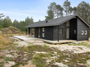 une maison noire dans un champ avec des arbres dans l'établissement Holiday Home Turkka - 3-8km from the sea by Interhome, à Tagholm