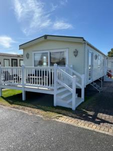 a mobile home with a porch and a white railing at 2 Bedroom Mini Lodge near the beach in Walton-on-the-Naze