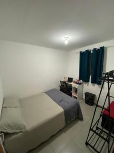 a bedroom with a bed and a desk and blue curtains at Cantinho da Giza-próx à praia em JP in João Pessoa +24 photos