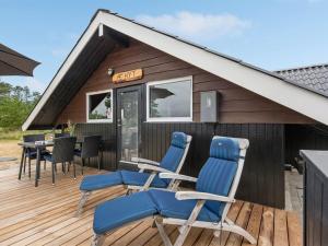 a wooden deck with chairs and a table on it at Holiday Home Torbjörn - 1-1km from the sea by Interhome in Mølby