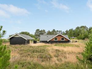 two houses in a field with trees in the background at Holiday Home Torbjörn - 1-1km from the sea by Interhome in Mølby