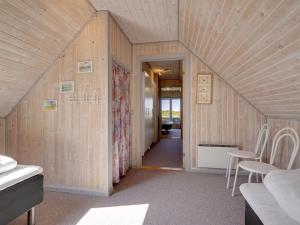a room with wooden walls and a hallway with chairs at Holiday Home Helfrida - 350m from the sea by Interhome in Lakolk