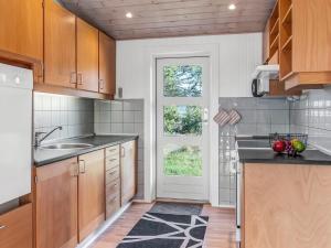 a kitchen with wooden cabinets and a sink and a window at Holiday Home Dietmar - 2-8km from the sea by Interhome in Kongsmark