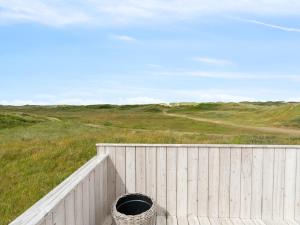 a wooden fence with a barrel in a field at Holiday Home Betti - 200m from the sea by Interhome in Lakolk