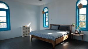 a bedroom with a bed with blue walls and windows at MayHome Binh Dinh in An Hòa