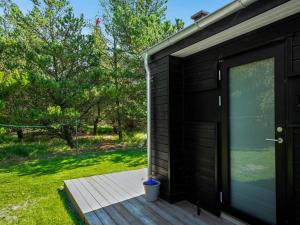 a black shed with a door and a deck at Holiday Home Tea - 2-7km from the sea by Interhome in Bolilmark