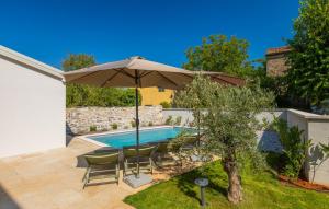 a patio with an umbrella and chairs and a pool at Villa Andrea by Villas Guide in Kurjavići