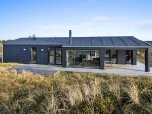 a house with a black roof on the beach at Holiday Home Jirina - 750m from the sea by Interhome in Vejers Strand
