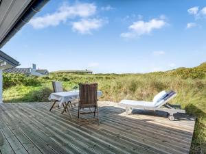 a deck with a table and chairs and a bench at Holiday Home Aise - 75m from the sea by Interhome in Vejers Strand