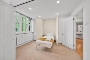 a white bedroom with a bed and a window at Luxury Spacious 3 Bedroom, 3 Bathroom Apartment, Walk to Soho, West End, Covent Garden, China Town, Piccadilly in Minutes, Complimentary Fast WiFi, Tea & Coffee in London