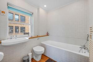 a bathroom with a tub and a toilet and a sink at Luxury Spacious 3 Bedroom, 3 Bathroom Apartment, Walk to Soho, West End, Covent Garden, China Town, Piccadilly in Minutes, Complimentary Fast WiFi, Tea & Coffee in London