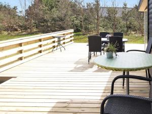 une terrasse en bois avec une table et des chaises dessus dans l'établissement Holiday Home Dane - 500m from the sea by Interhome, à Blåvand