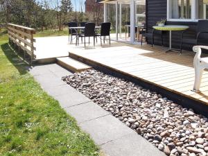 une terrasse avec une table, des chaises et des rochers dans l'établissement Holiday Home Dane - 500m from the sea by Interhome, à Blåvand