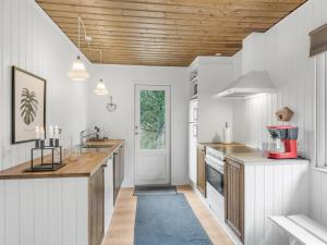 a kitchen with white cabinets and a wooden ceiling at Holiday Home Magrete - 900m from the sea by Interhome in Blåvand +8 photos