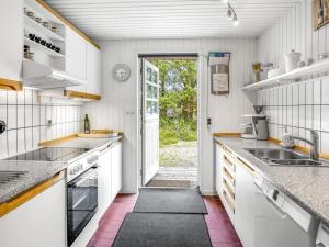 une cuisine avec comptoirs blancs et une porte donnant sur une cour dans l'établissement Holiday Home Lilo - 1km from the sea by Interhome, à Blåvand