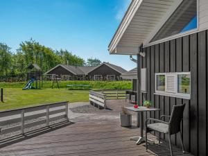 a deck with a table and chairs and a playground at Holiday Home Domna - 800m from the sea by Interhome in Blåvand