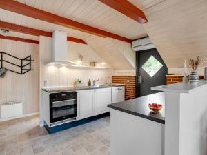 - une cuisine avec des placards blancs et une cuisinière noire dans l'établissement Holiday Home Görel - 1km from the sea by Interhome, à Blåvand