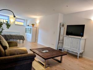 ein Wohnzimmer mit Sofa, Fernseher und Tisch in der Unterkunft Quartier Allna in Allna