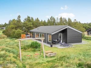 une petite maison avec une aire de jeux dans un champ dans l'établissement Holiday Home Soili - 1-2km from the sea by Interhome, à Blåvand
