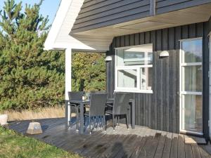une terrasse avec une table et des chaises dans une maison dans l'établissement Holiday Home Tinemarie - 200m from the sea by Interhome, à Blåvand