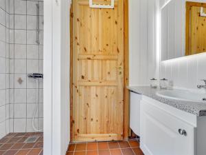 La salle de bains est pourvue d'une porte en bois et d'un lavabo. dans l'établissement Holiday Home Vladan - 1-6km from the sea by Interhome, à Blåvand