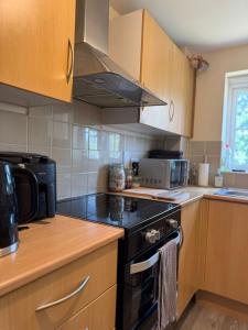 a kitchen with a black stove and a microwave at Spacious 2-Bedroom Flat Near Shops & Transport in Newbury