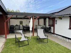 a patio with two chairs and an umbrella on the grass at Holiday Home Safina - from the sea by Interhome in Ringkøbing