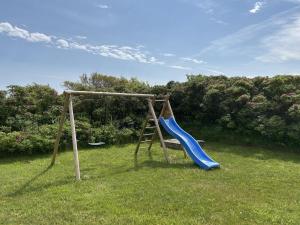 a playground with a blue slide in the grass at Holiday Home Safina - from the sea by Interhome in Ringkøbing +21 photos