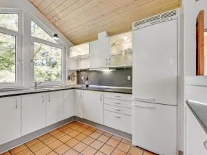 eine Küche mit weißen Schränken und einer Holzdecke in der Unterkunft Holiday Home Tali - 700m from the sea by Interhome in Ringkøbing