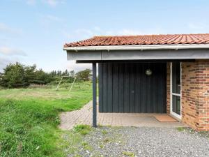 a small house with a black door in a field at Holiday Home Soini - 900m from the sea by Interhome in Ringkøbing +29 photos