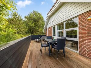 eine Terrasse mit einem Tisch und Stühlen auf einem Haus in der Unterkunft Holiday Home Sylvi - 1-7km from the sea by Interhome in Ringkøbing