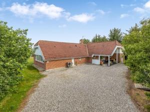 ein Backsteinhaus mit einem Dach auf einer Kieseinfahrt in der Unterkunft Holiday Home Sylvi - 1-7km from the sea by Interhome in Ringkøbing