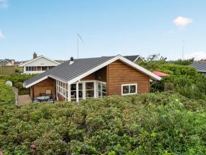 a wooden house on a hill with bushes at Holiday Home Geeske - 400m from the sea by Interhome in Ringkøbing