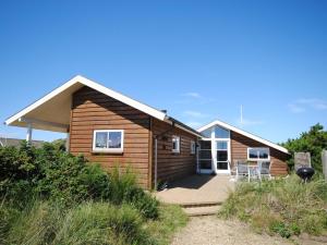 a small wooden house with a porch and a patio at Holiday Home Geeske - 400m from the sea by Interhome in Ringkøbing