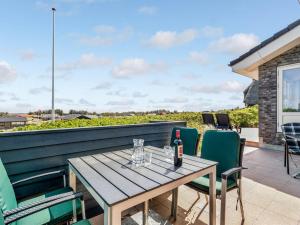 a table with a bottle of wine and chairs on a patio at Holiday Home Edle - 300m from the sea by Interhome in Ringkøbing