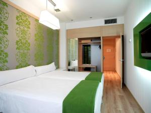 a bedroom with a white bed and a television at NH La Avanzada in Leioa +19 photos