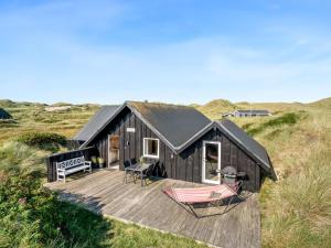 a black house with a deck and a hammock at Holiday Home Eggert - from the sea by Interhome in Ringkøbing +26 photos