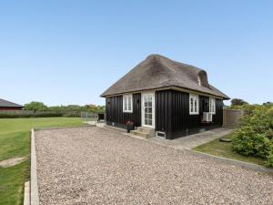 a black cottage with a thatched roof and a gravel driveway at Holiday Home Ulva - 400m from the sea by Interhome in Ringkøbing